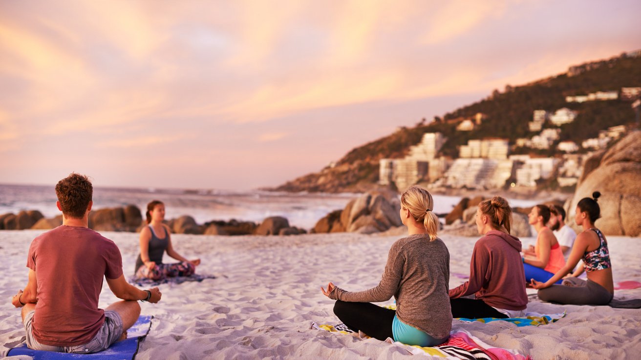 Reisegruppe übt Yoga am Strand